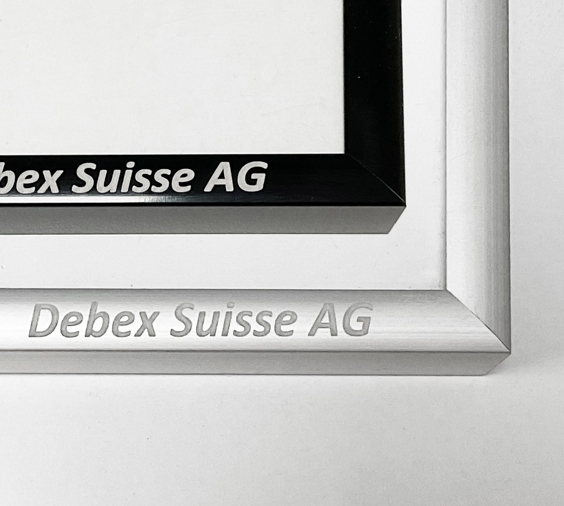 Close-up of laser engraving on a silver metal frame and custom printing on a black frame for Debex Suisse AG.
