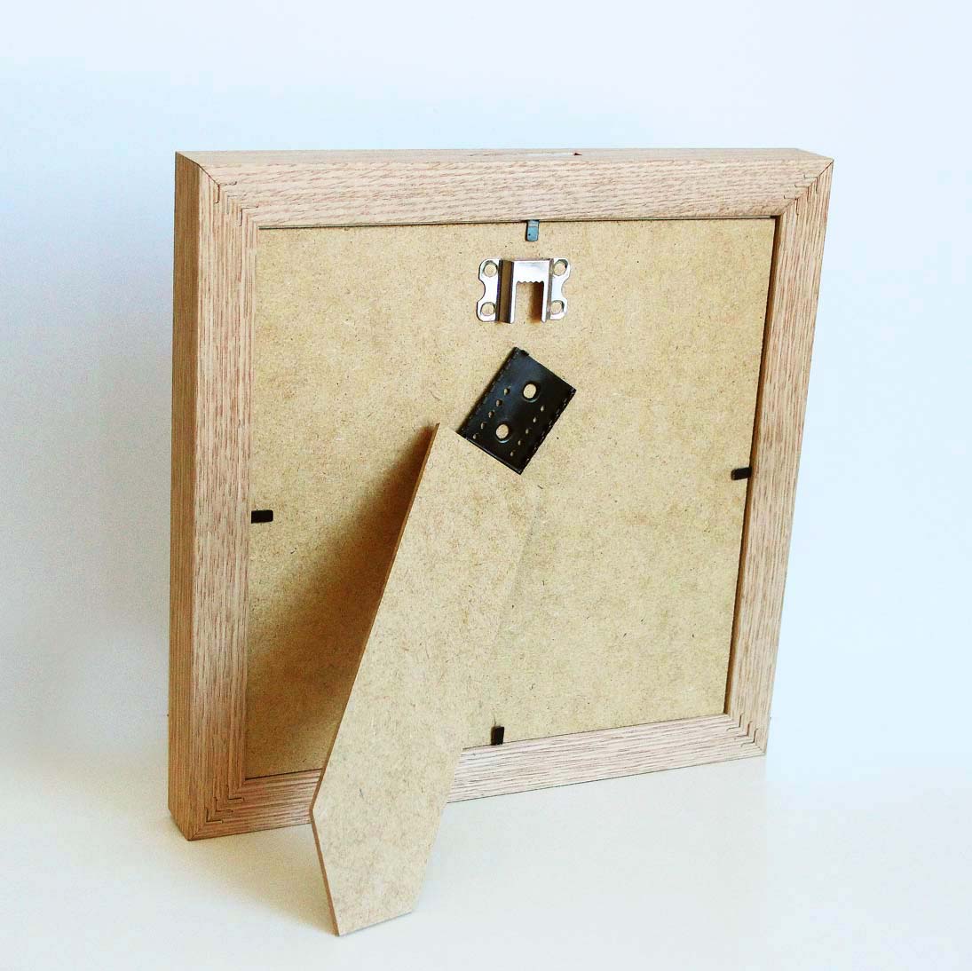 Oak wood frame made as money box, with 3D effect and slot for money, backside with adjustable easel and sawtooth hanger. Picture frame producer Debex Suisse.