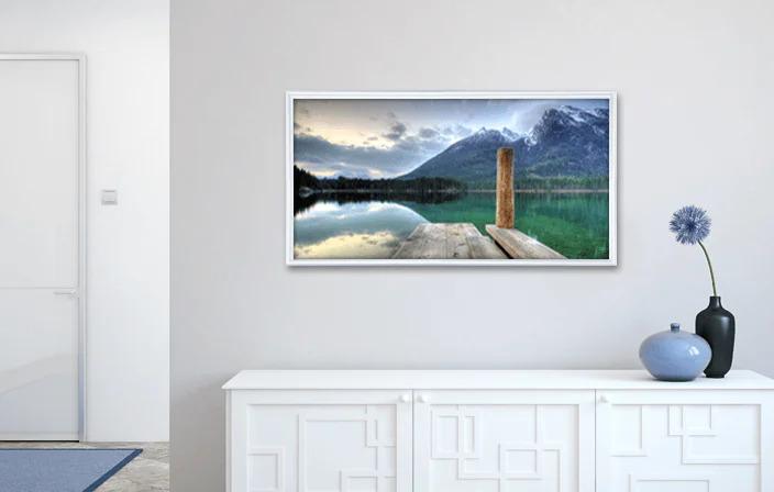 Landscape wall art featuring a mountain lake with a wooden pier displayed above a white sideboard